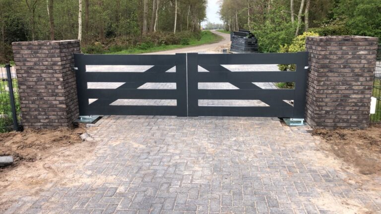 Dubbele stalen inrijpoort tussen gemetselde poeren op een oprit